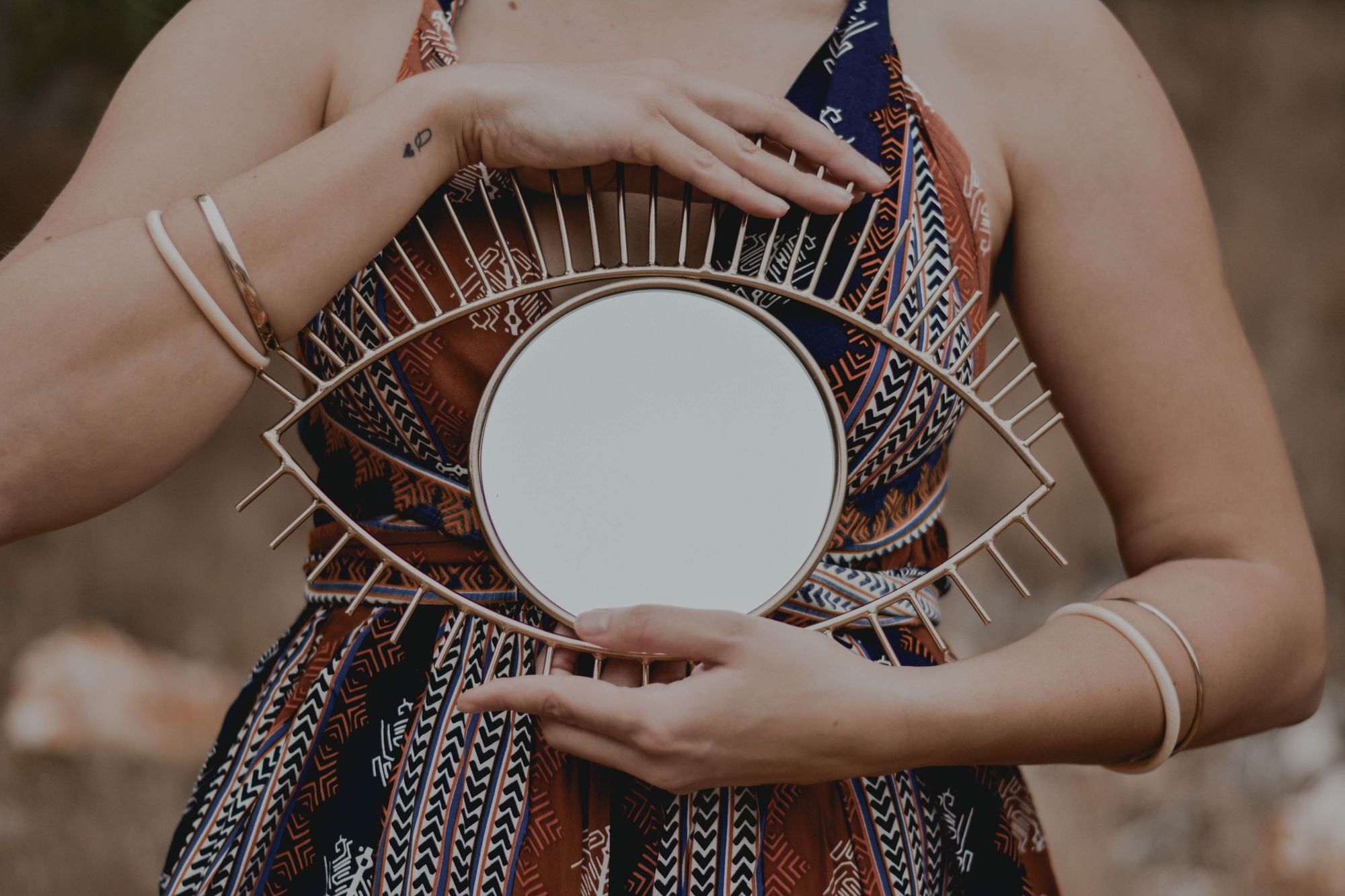 Image of woman holding a mirror framed in a way to appear as if the mirror is an eye